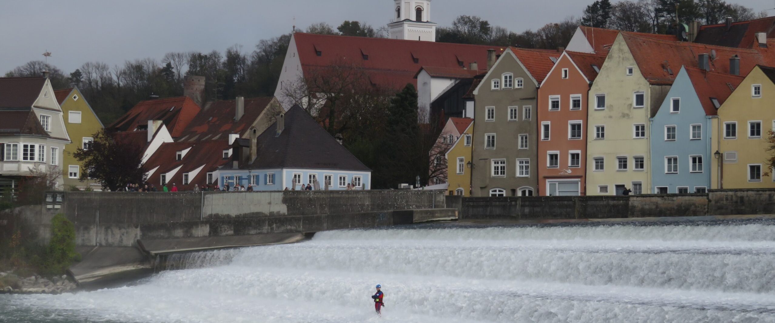 Ein Wasserretter steht im Landsberger Lechwehr. Im Hintergrund sieht man die landsberger Altstadt