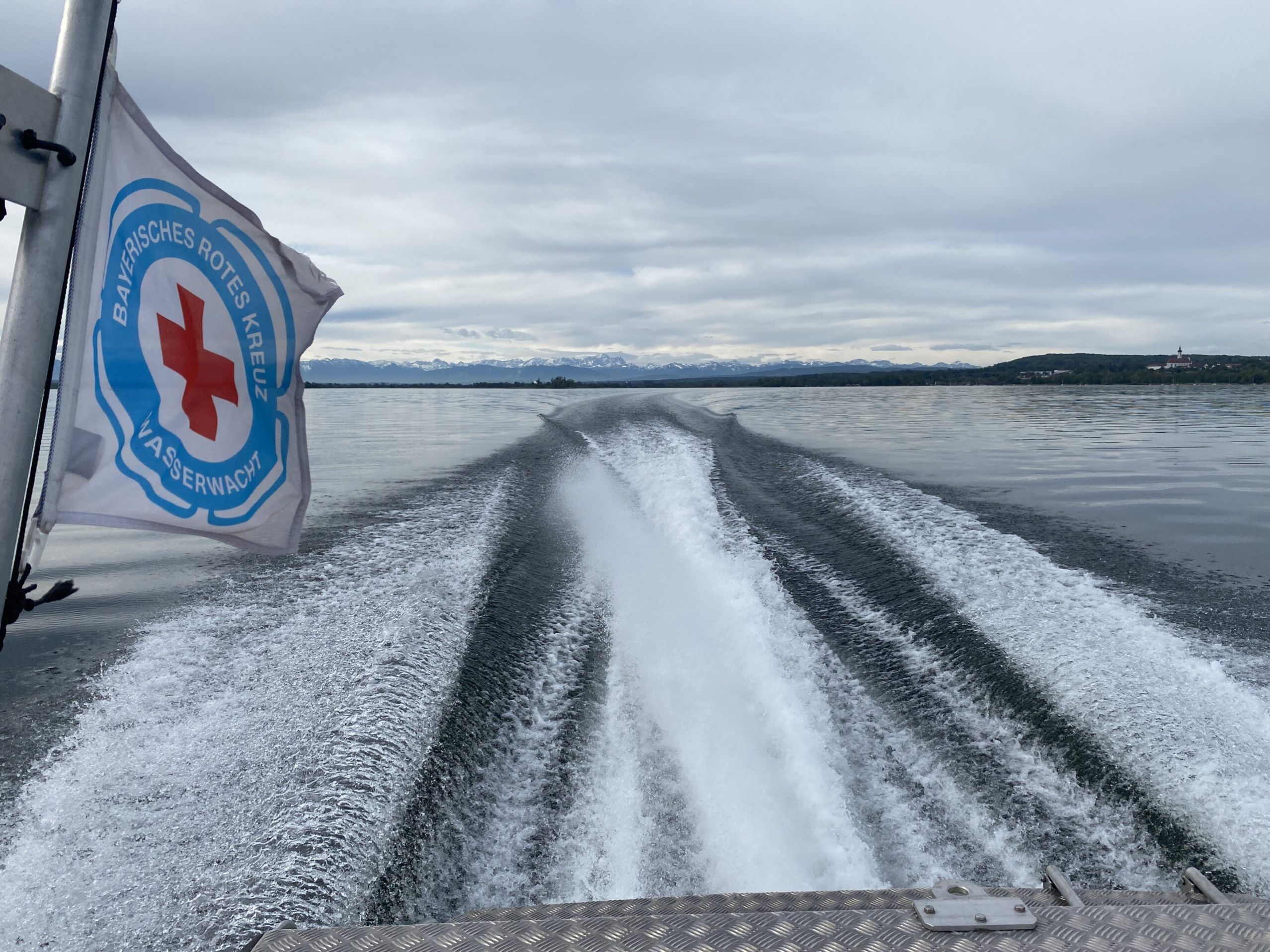 Blick achteraus von einem Motorrettungsboot in voller Fahrt auf dem Ammersee mit Blick auf die Berge