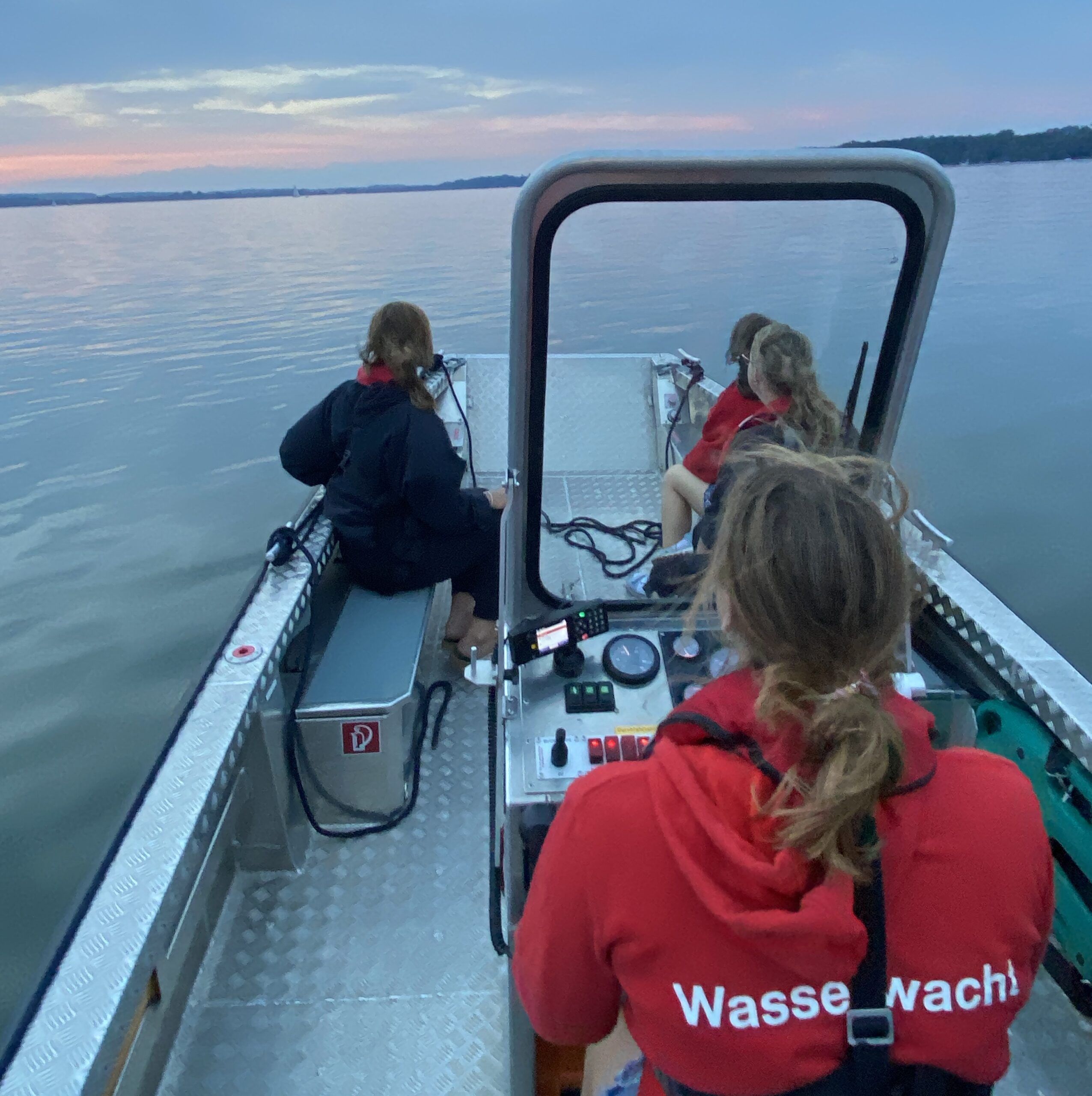 Symbolbild: Motorrettungsboot der Wasserwacht auf Einsatzfahrt auf dem Ammersee. Blick achteraus auf die wehende WW Fahne vor dem Horizont